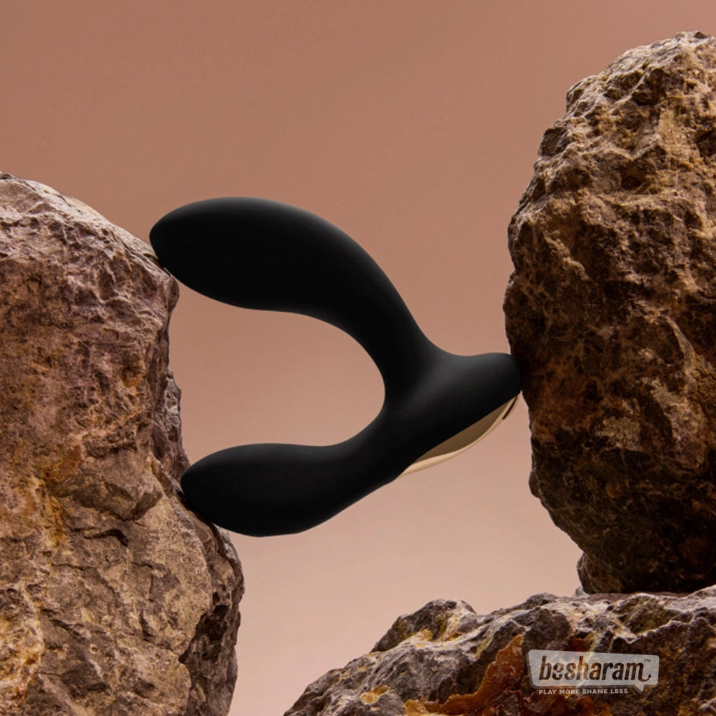 LELO Hugo 2 black prostate massager placed between two rocks in a creative studio setup