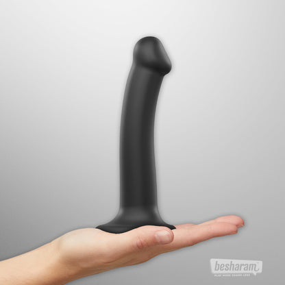 Black strap on dildo displayed on hand showing length and curved tip, bendable silicone dildo with suction base