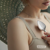 Woman holding the Viben Cheeky Charms silver heart butt plug near chest in a lifestyle setting