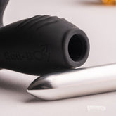 Close-up detail of a black Bad-Boy prostate massager with a silver bullet vibrator placed beside the sleeve opening.