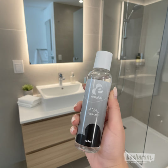 Hand holding EasyGlide anal lubricant 150ml in modern bathroom setting for lifestyle product display