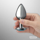 Gunmetal butt plug with wide suction base shown held in hand to display size and smooth stainless steel finish