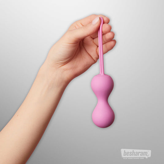 Hand holding the Joia Kegel balls to show size and ergonomic design.