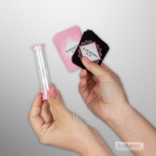 Hands holding the Kamasutra Play cards and pink one minute hourglass on a light background