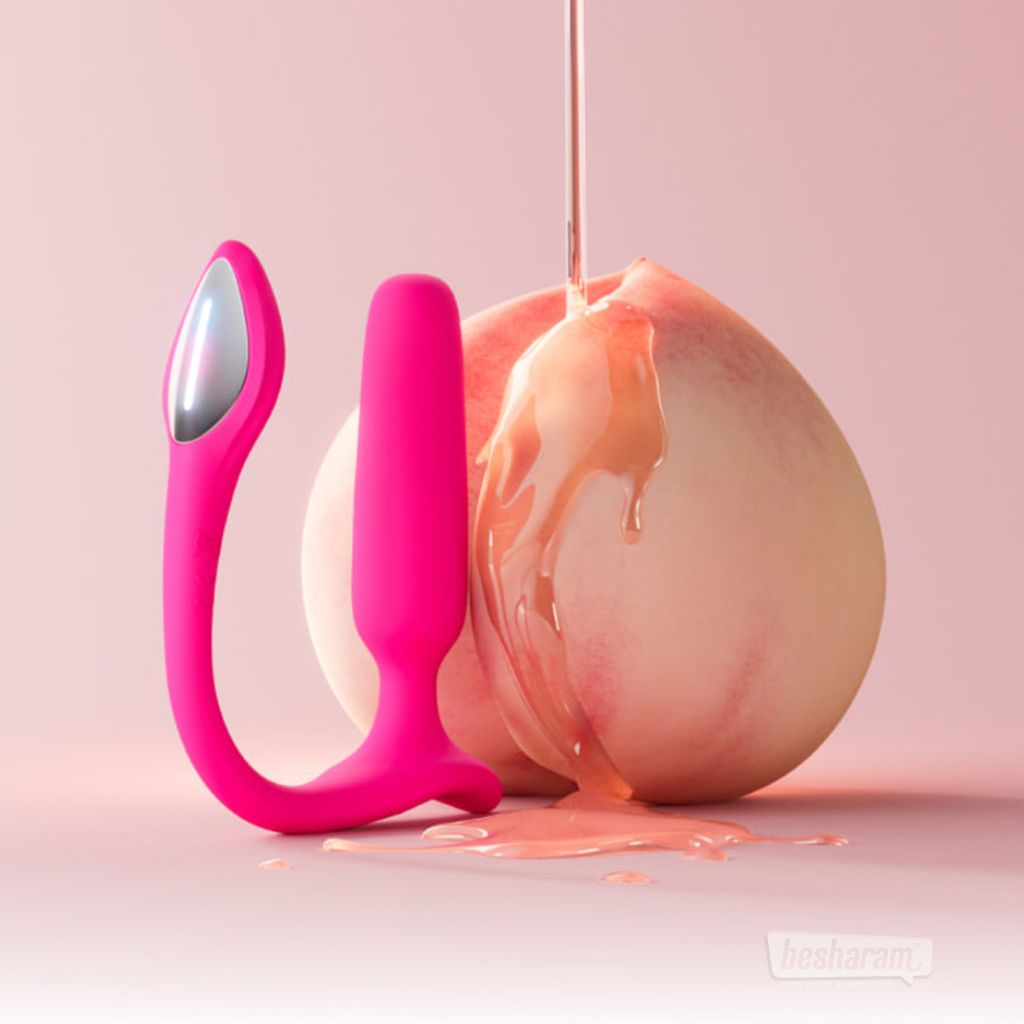 Lovense Lush Anal smart butt plug app controlled pink vibrator placed beside peach with water based lubricant for lifestyle display