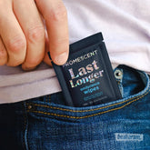 Hand placing a Promescent Last Longer endurance wipes sachet into a jeans pocket.