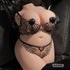 Realistic torso love doll dressed in black lace lingerie, posed seated on a leather surface.
